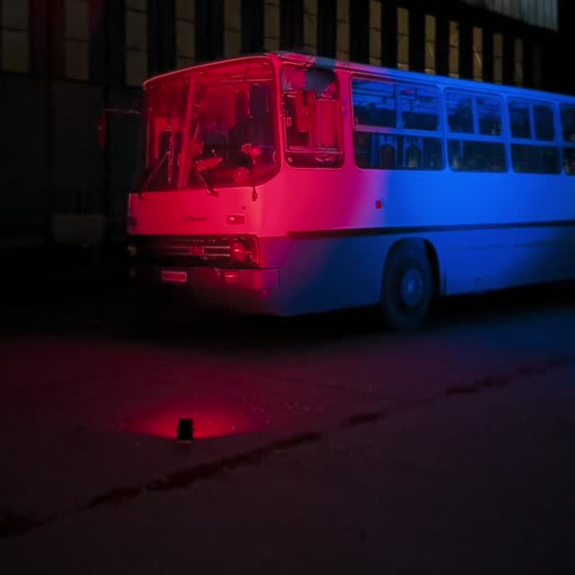 Ikarus-Bus bei Nacht in rotem und blauem Licht